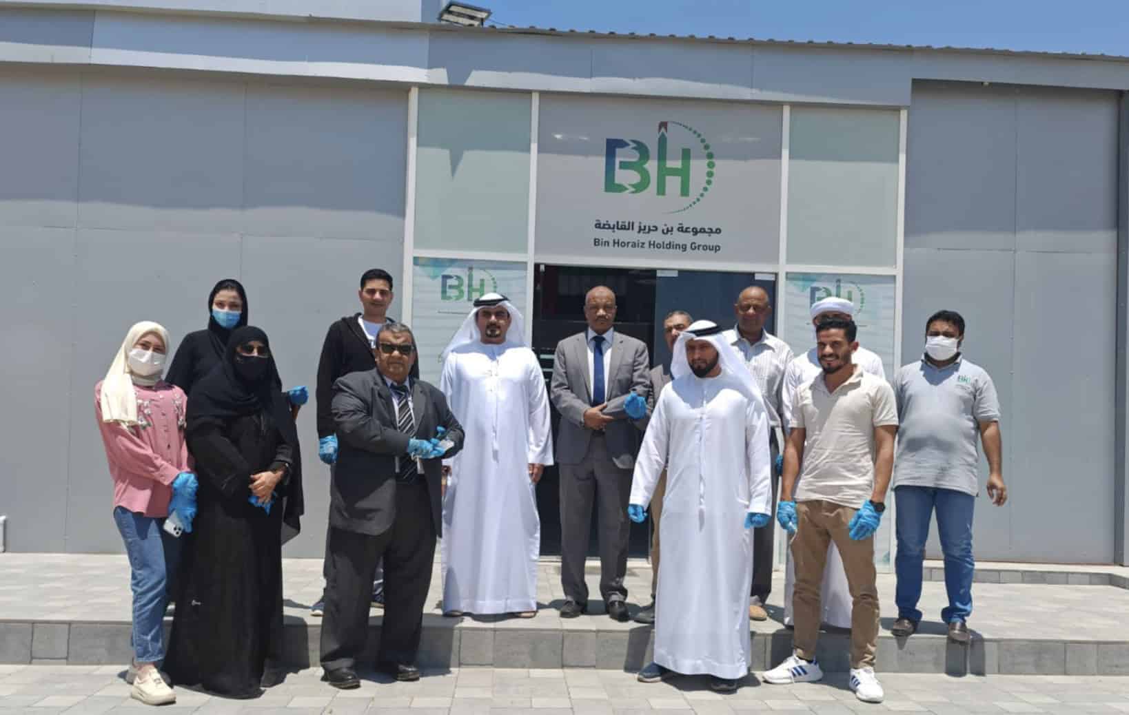 NJS Tech team at Bin Horaiz Holding Group headquarters, showcasing a diverse group of professionals in front of company signage.