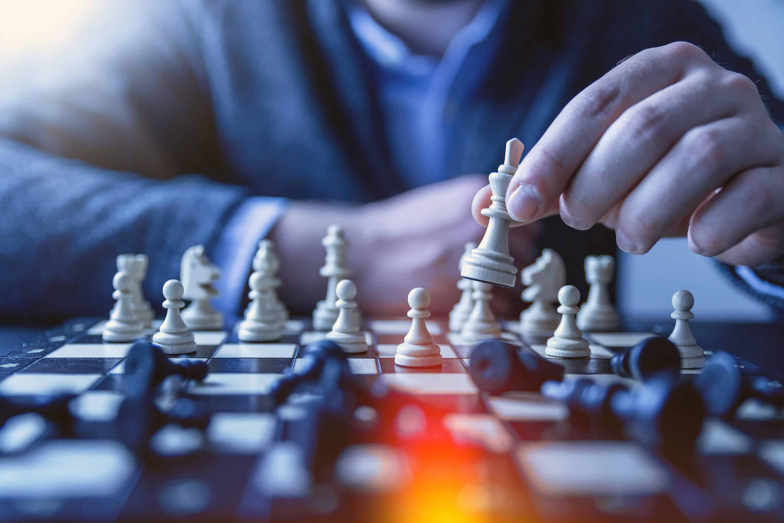 jeshoots-com-fzOITuS1DIQ-unsplash Strategic chess game; person making move on chessboard with digital focus.